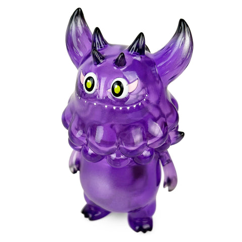 Rangeas Jr. — Clear Purple by The Little Hut is a translucent purple toy monster with large yellow eyes, two horns, pointed ears, and small back spikes, shown standing upright against a white background.