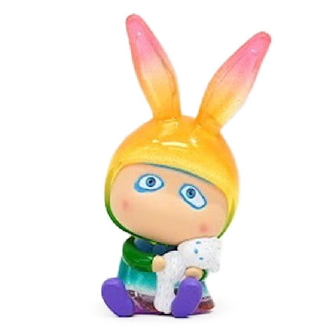 A-Boy — A Coral by How2Work: A small figurine of a child with large blue eyes, wearing a yellow and pink bunny-eared hood, holding a white textured item, and sitting with legs outstretched.