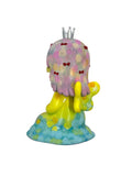 The Biwaco Chan figurine by How2Work features pastel hair, a silver crown, and a yellow body, seated on a blue and green base. Inspired by Japanese ceramic artist Aico Tsumori, the character faces away while holding a star-shaped object in one hand.