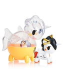 Two small tokidoki Unicorno Capsule Cuties Blind Box figurines—one clear with yellow and black bee designs, the other mostly white with black, gold, and red—are displayed side by side on a white background.