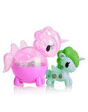 The tokidoki Unicorno Capsule Cuties Blind Box includes two pastel unicorns: a pink, transparent one with wings, and a light blue one with green hair and daisy patterns.