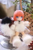 A BIJIDI Cat Island — Black Cat Or Candy Cat? Blind Box ball-jointed doll with pink hair and a fluffy white outfit sits on a cushion beside a decorative plant basket.