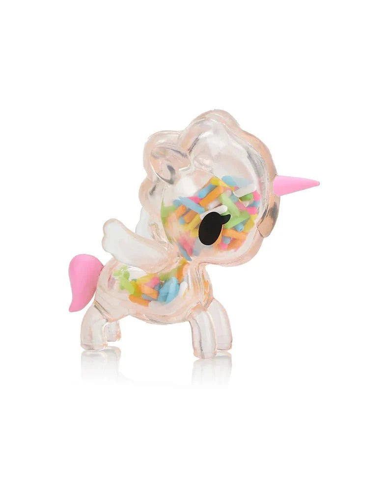 The Toki Mochi Donut Unicorno Blind Bag by tokidoki features a clear unicorn with a pink horn and tail, filled with colorful sprinkles—ideal for fans of squishy Unicornos or collectors of the Donut Unicorno Blind Box series.