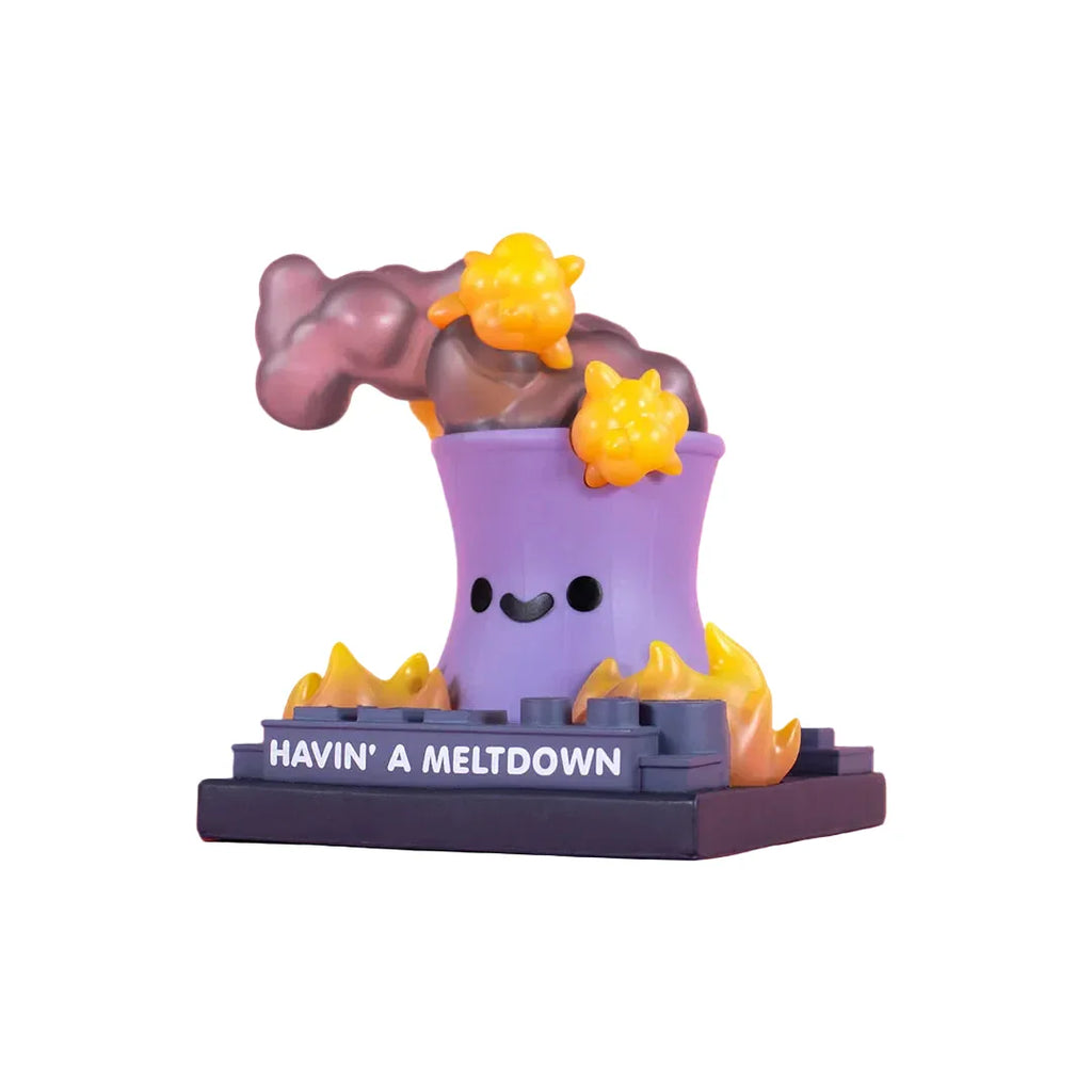 The 100% Soft Lil Meltdown Vinyl Figure is a cartoonish purple nuclear reactor cooling tower with a smiling face, surrounded by yellow flames and smoke, sitting on a base labeled 