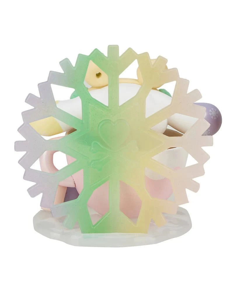 A pastel snowflake-shaped item with a heart detail stands before stacked mugs, adding charm to your space—it's the Special Edition tokidoki x Hello Kitty and Friends Winter Dreams Cinnamoroll by tokidoki.