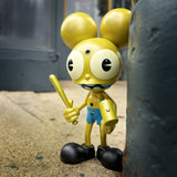 The Dalek Space Monkey — Gold Rotofugi Exclusive by UVD Toys is a collectible vinyl toy featuring a gold cartoon monkey with large ears, blue shorts, and black shoes, playfully posed on a city sidewalk next to a green pole.