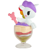 A delightful tokidoki Shaved Ice Dreams Unicorno Blind Box figure with a purple hat rests atop a layered dessert in a glass, accented by a pink bear-shaped stir stick—an irresistible collectible for any fan.