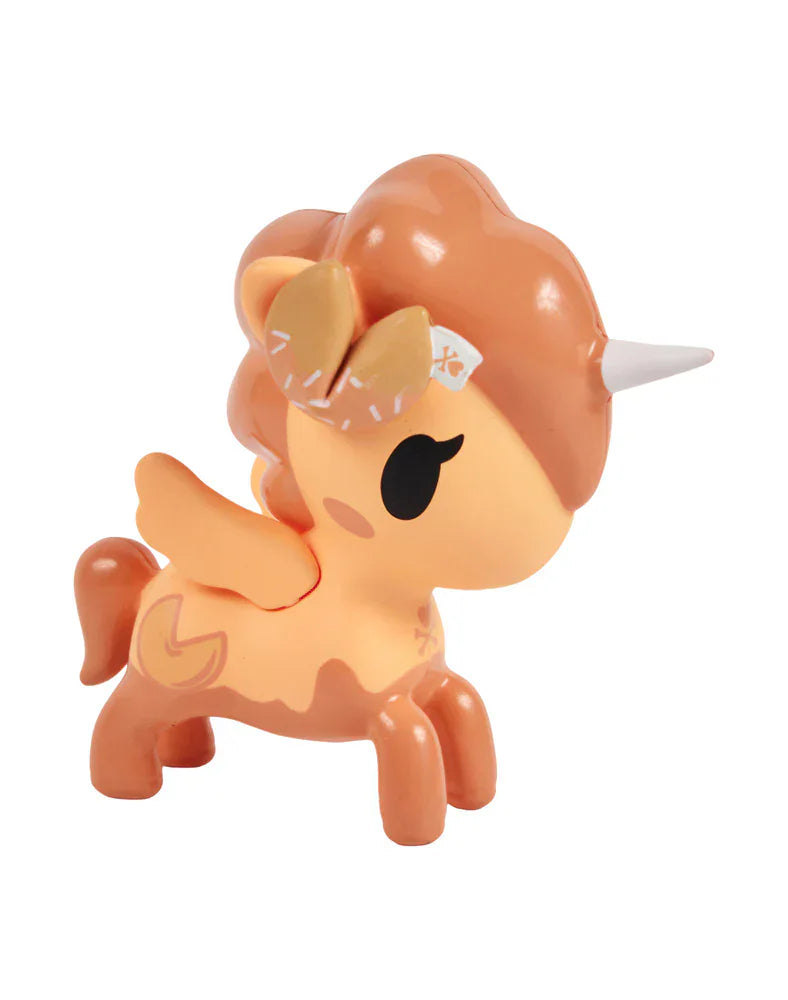 A small orange and cream toy unicorn with wings, a white horn, and closed eyes stands on four legs. This delightful surprise figure is from the tokidoki Fortune Cookie Unicorno Blind Box collection.