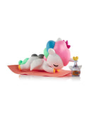 The tokidoki Spa Day Unicorno Blind Box features a cute Unicorno figurine with a colorful mane, face-down on a pink mat beside a small bottle with a yellow heart cap—perfect for adding kawaii wellness vibes to your space.