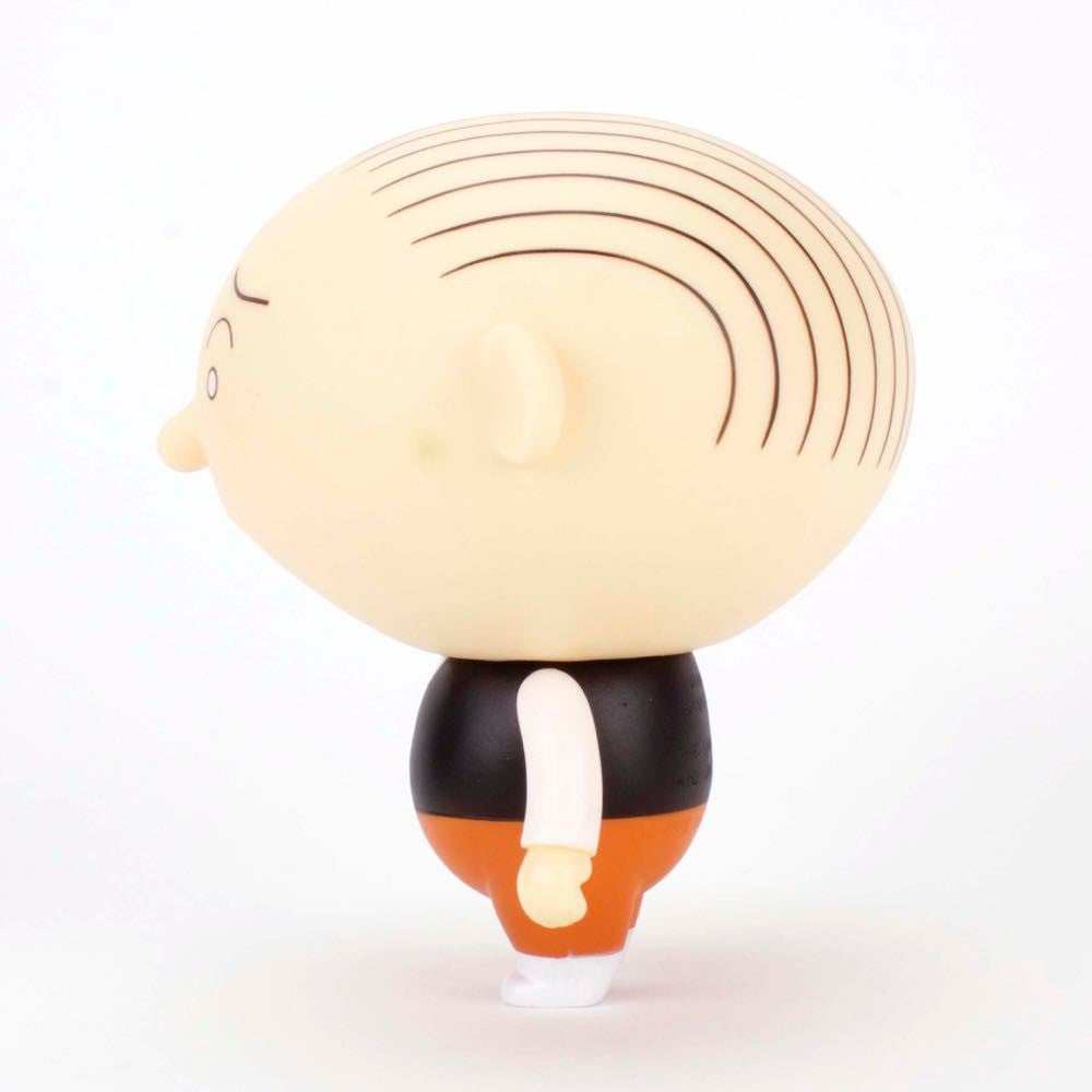 Side view of the Presspop Jimmy Corrigan Vital Animus Vinyl Doll, a cartoonish bald figure with black head stripes, black vest, white sleeves, orange pants, and white shoes, posed against a plain white background.