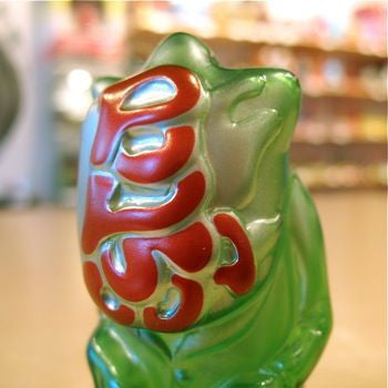 A close-up of the Pop Soda Popsoda Finger Puppet - Clear Green, featuring red and white markings on its back, set against a blurred indoor background.