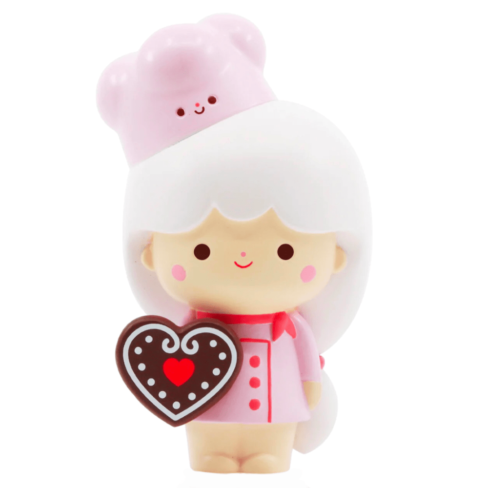 The Momiji Sweetie - 5 Inch doll by Momiji features white hair, a pink outfit, and a pink bear hat holding a heart-shaped chocolate—an adorable gift or baking buddy for anyone who loves cute collectibles.