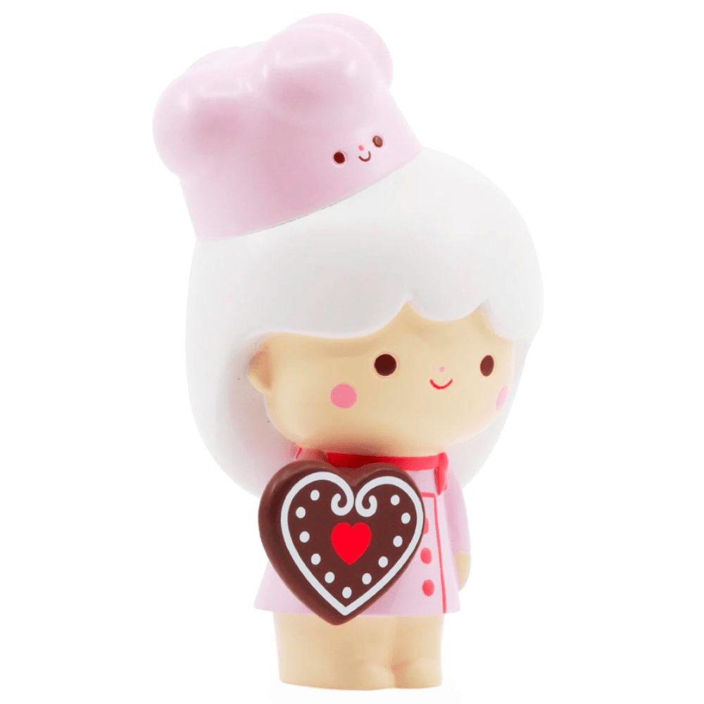 Momiji Sweetie - 5 Inch by Momiji features a white-haired doll in a pink chef’s hat and outfit, holding a heart-shaped chocolate with dots and a red heart—the perfect baking companion.