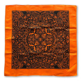 The Cherry Moth Cake Bandana by Cherry Moth Cake features an orange square with a black symmetrical design, detailed patterns, and shapes radiating from the center.
