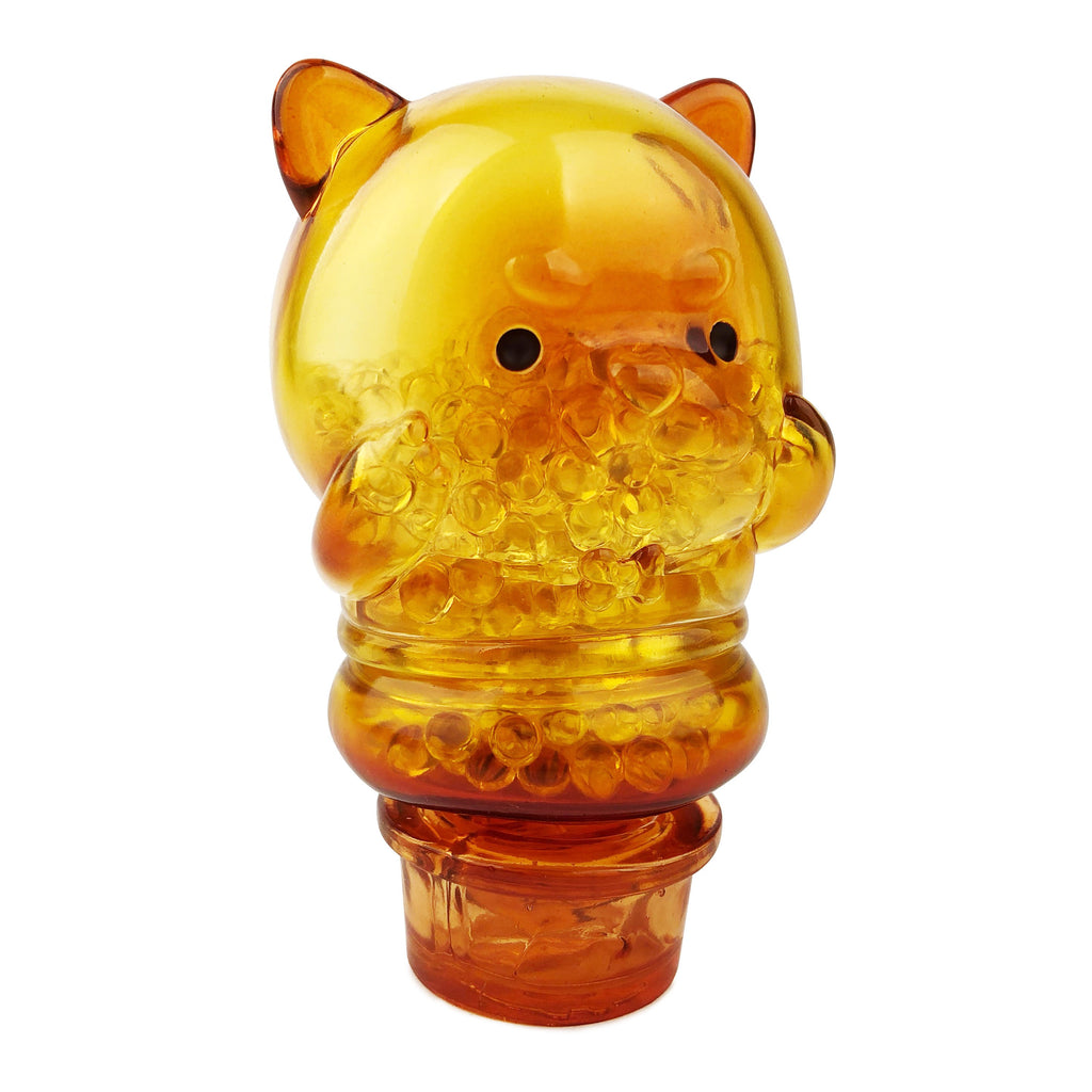 A translucent amber Meng Meng Bing — Dog Popsicle Mini-Figure by Sun Day Toy, shaped like a cartoon pup with cat-like ears and round black eyes, stands upright with paws near its face—ideal for fans of cute animal figures.