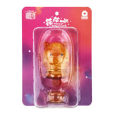 A small, amber-colored Meng Meng Bing — Dog Popsicle Mini-Figure from Sun Day Toy comes sealed in a clear blister pack with a colorful gradient backing featuring logos and text—perfect for fans of animal-shaped toys.
