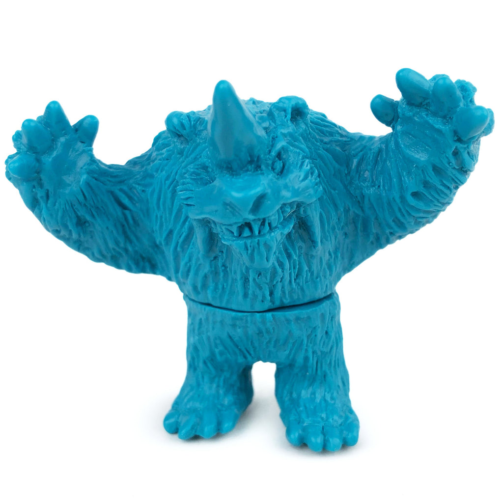 Blue plastic toy figure of a furry monster with one horn, raised arms, and a wide grin. The Neo-Fighters X Rotofugi 312 Edition by Geoff Maxfield is part of the Battle City Tournament Mile High Sofubi series.